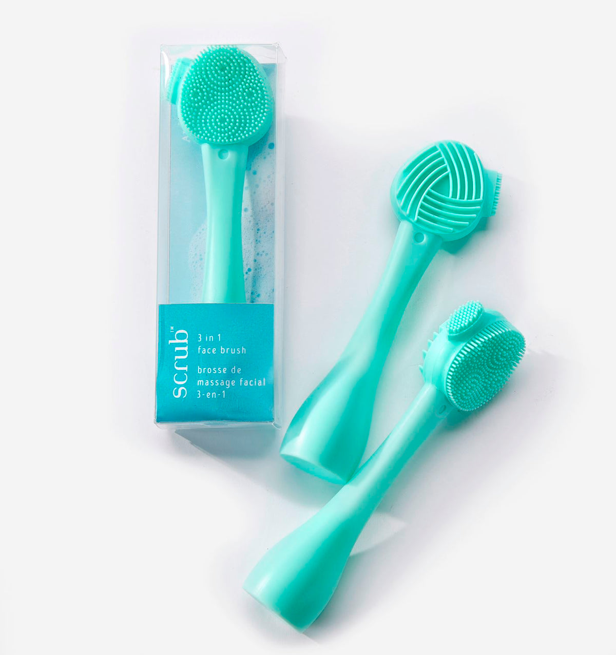 Three teal 3-in-1 face brushes and massagers, one in its clear packaging and two lying next to it.