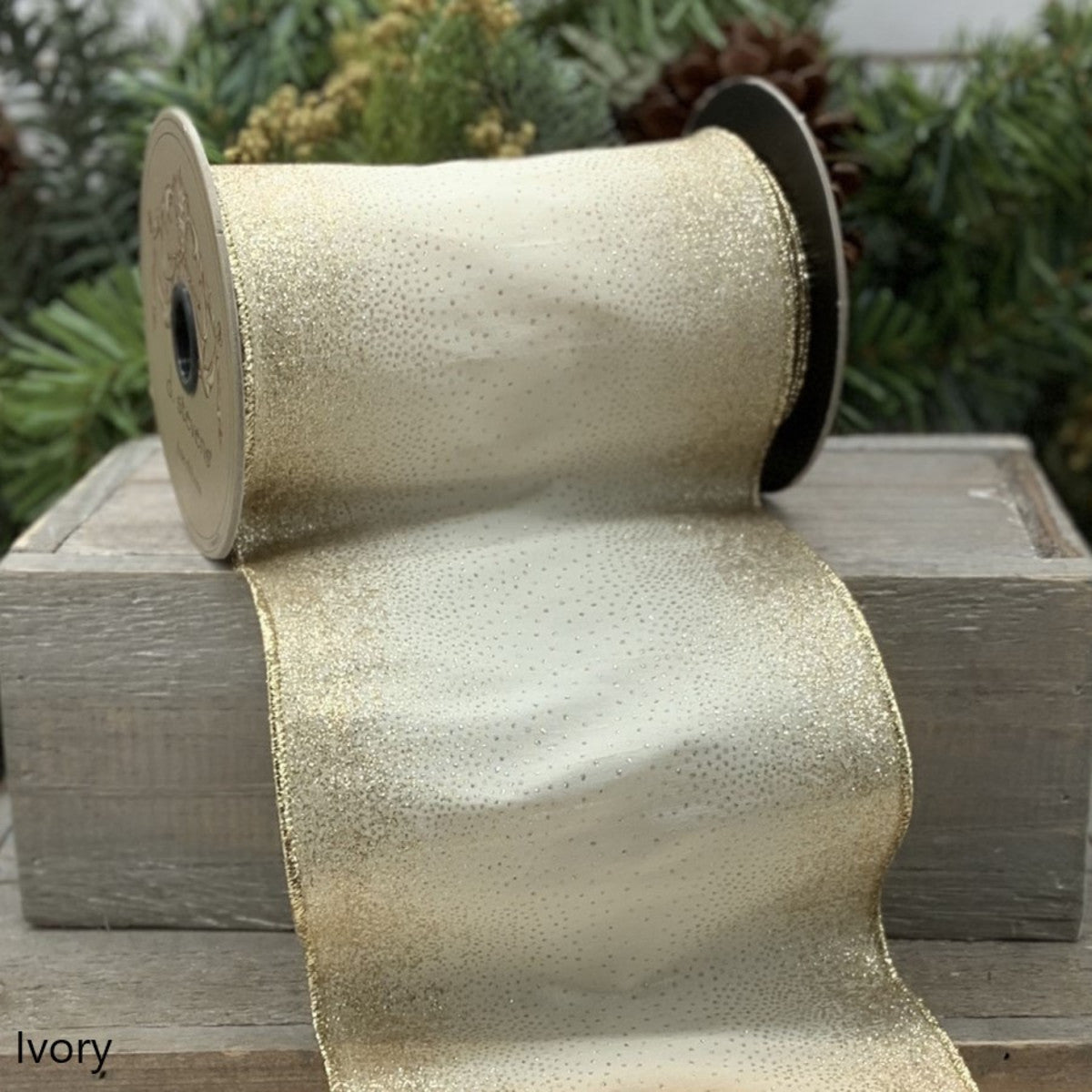 5 inch wide ivory faux dupion ribbon with gold starburst glitter edges on a wooden crate.