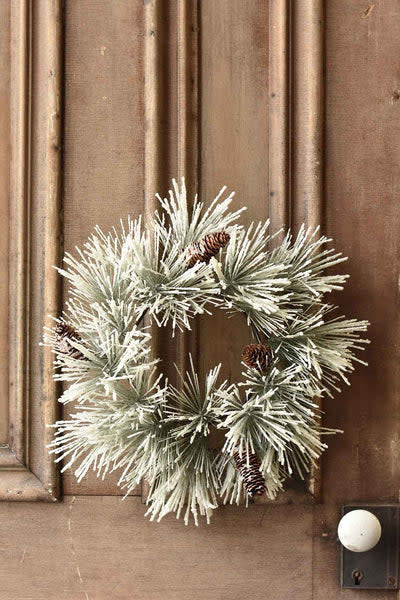 Round snowy pine wreath with icy finish, glitter coating on needles, natural cones, and wire base.
