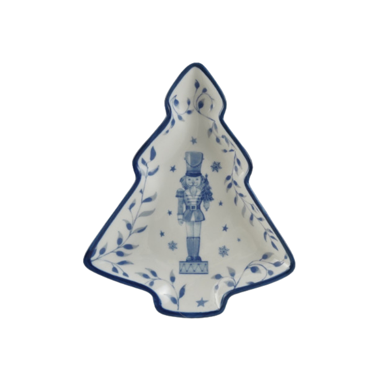 Christmas tree-shaped ceramic dish in white and blue with a nutcracker and vine pattern.