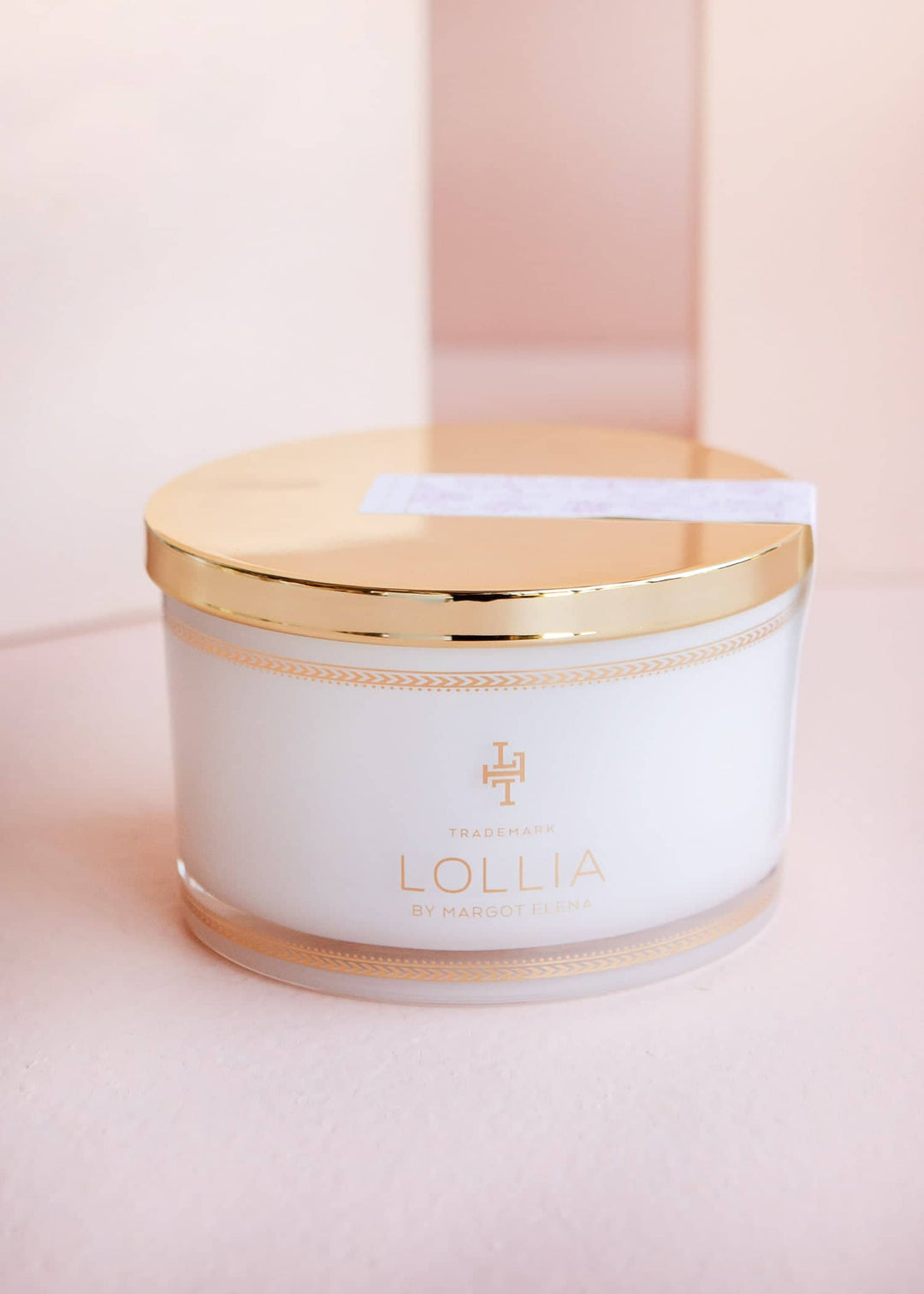 White glass jar with gold accents holding sea salt in a linen bag