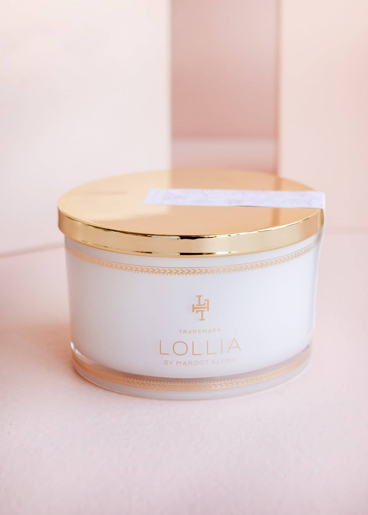 White glass jar with gold accents holding sea salt in a linen bag