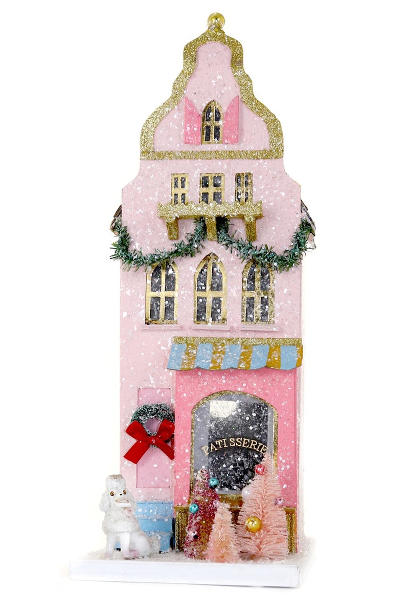 Pink glittery gingerbread-style house with gold trim, windows, a wreath, and a poodle.