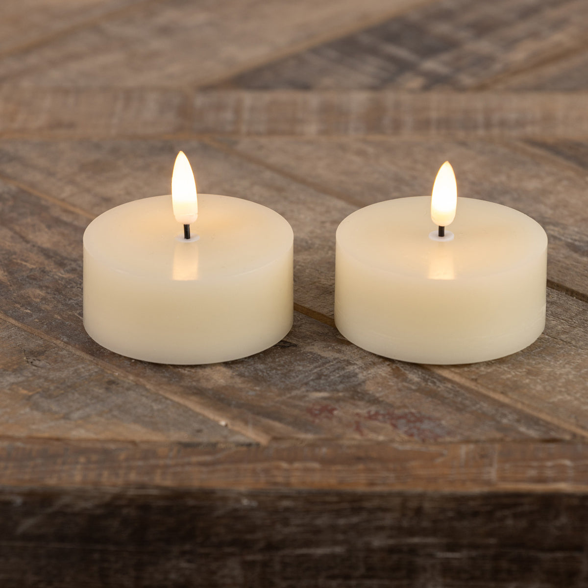Set of three cream-colored plastic tealight holders shaped like oversized flames with wax candles inside.