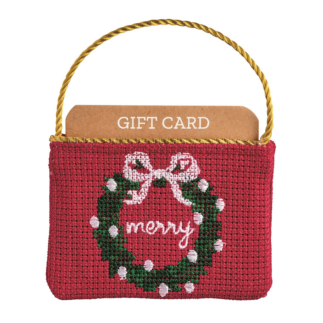 Red needlepoint gift card pouch with a green wreath, white bow, and 'merry' text.