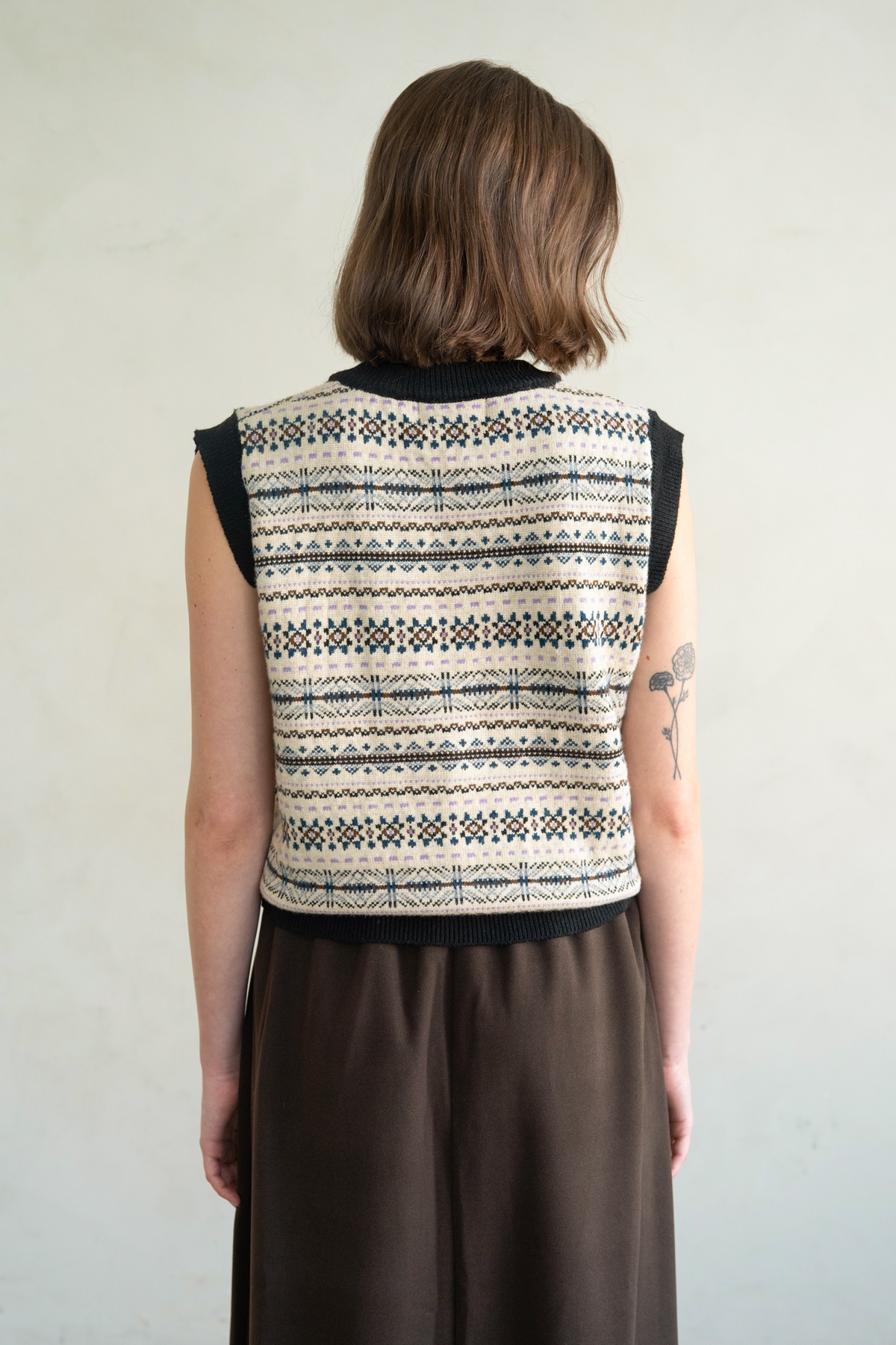 Back view of a person wearing a Via Relaxed Fit Knit Sweater Vest with a fair isle pattern.
