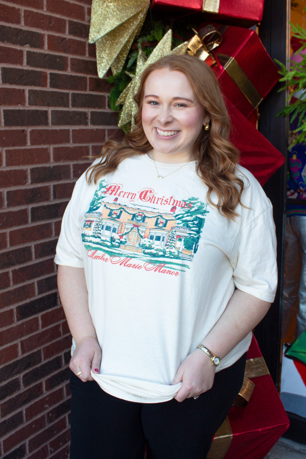 Ivory Christmas t-shirt featuring an illustrated design of a decorated manor with the text Merry Christmas Amber Marie Manor.