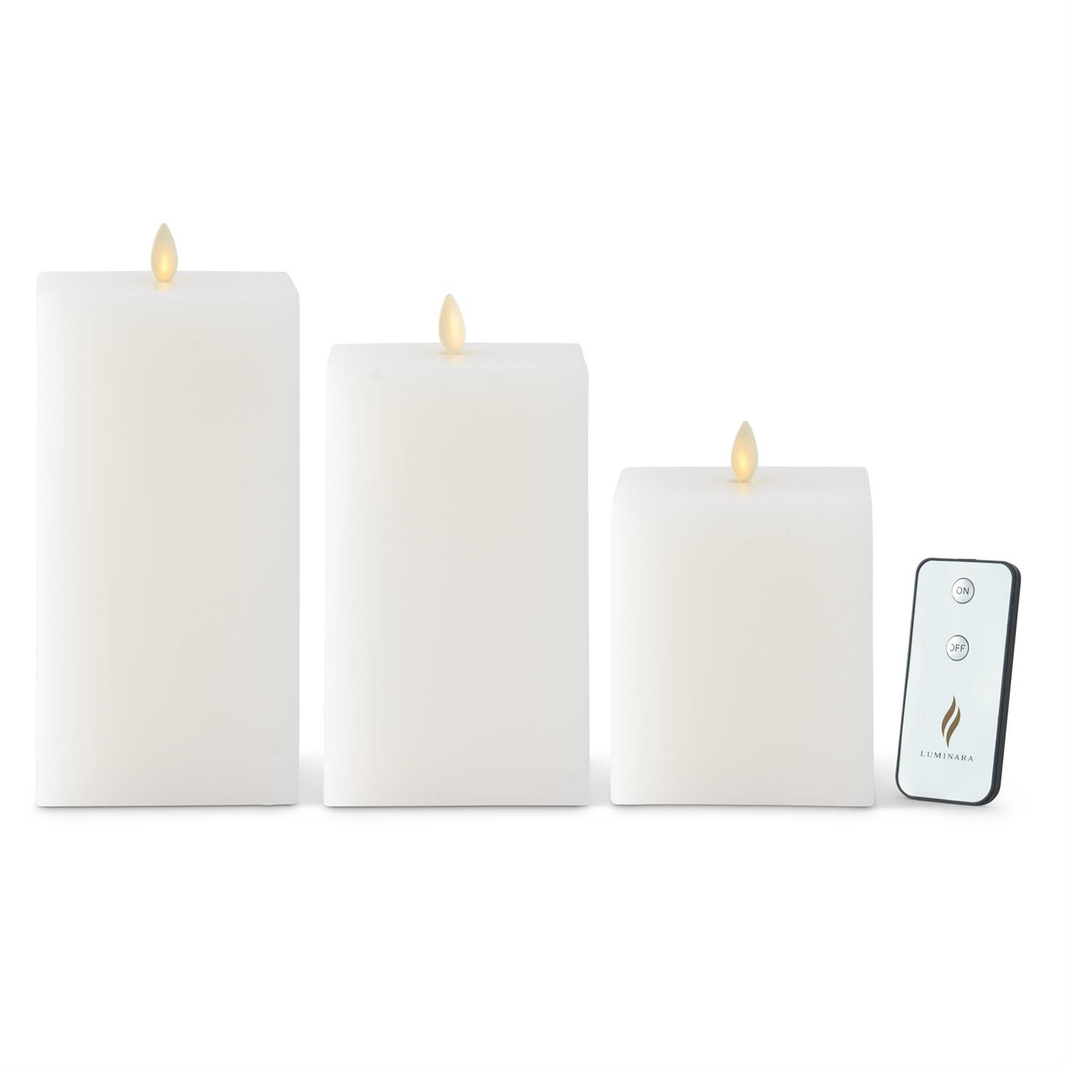 Three white square Luminara flameless wax candles in varying heights with a remote control.