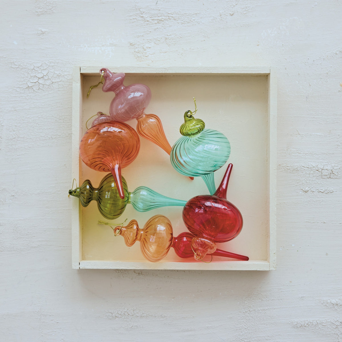 Assorted two-tone glass finial ornaments in a wooden box, featuring ribbed textures and gradients.