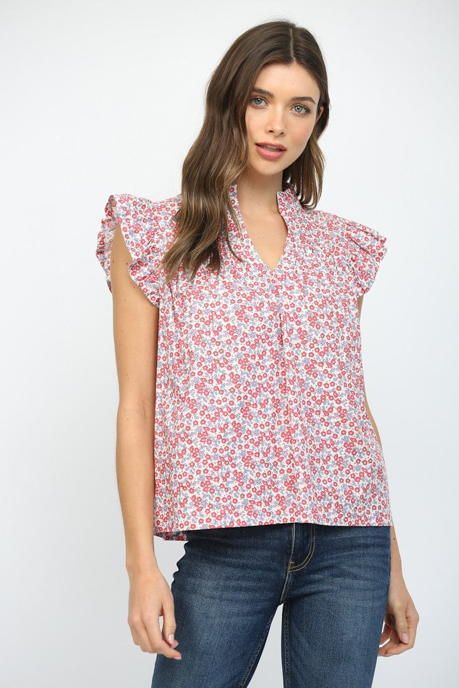 Woman wearing a Hannah Flutter Sleeve Top with a V-neck and red and blue floral print.