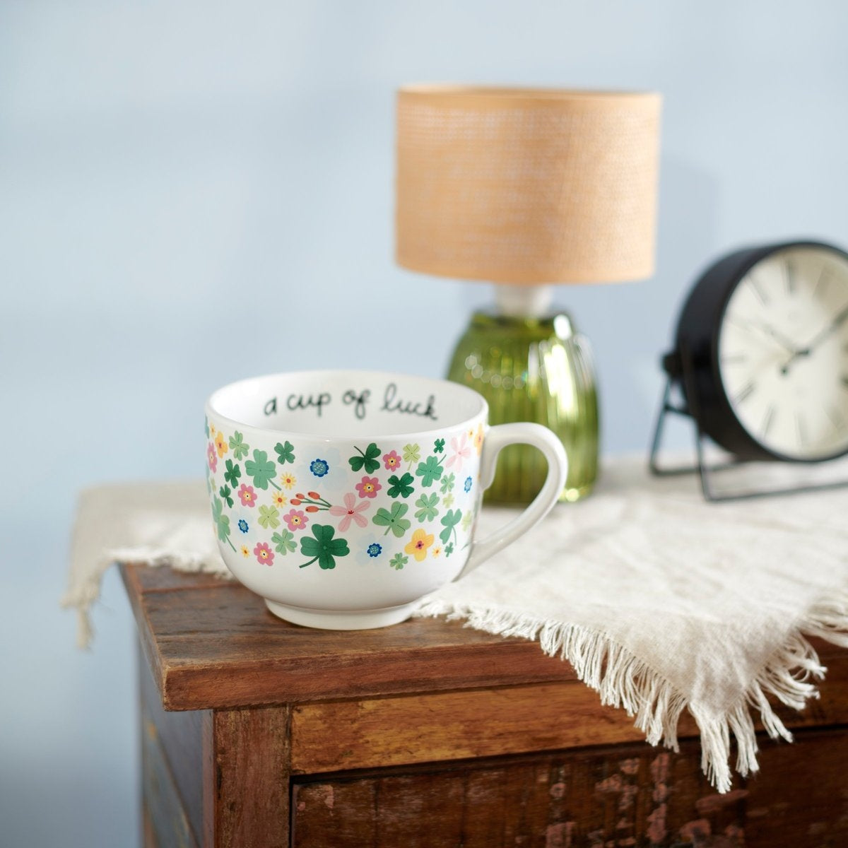 A white stoneware mug with a rounded handle featuring the text 'A Cup of Luck' in black lettering.