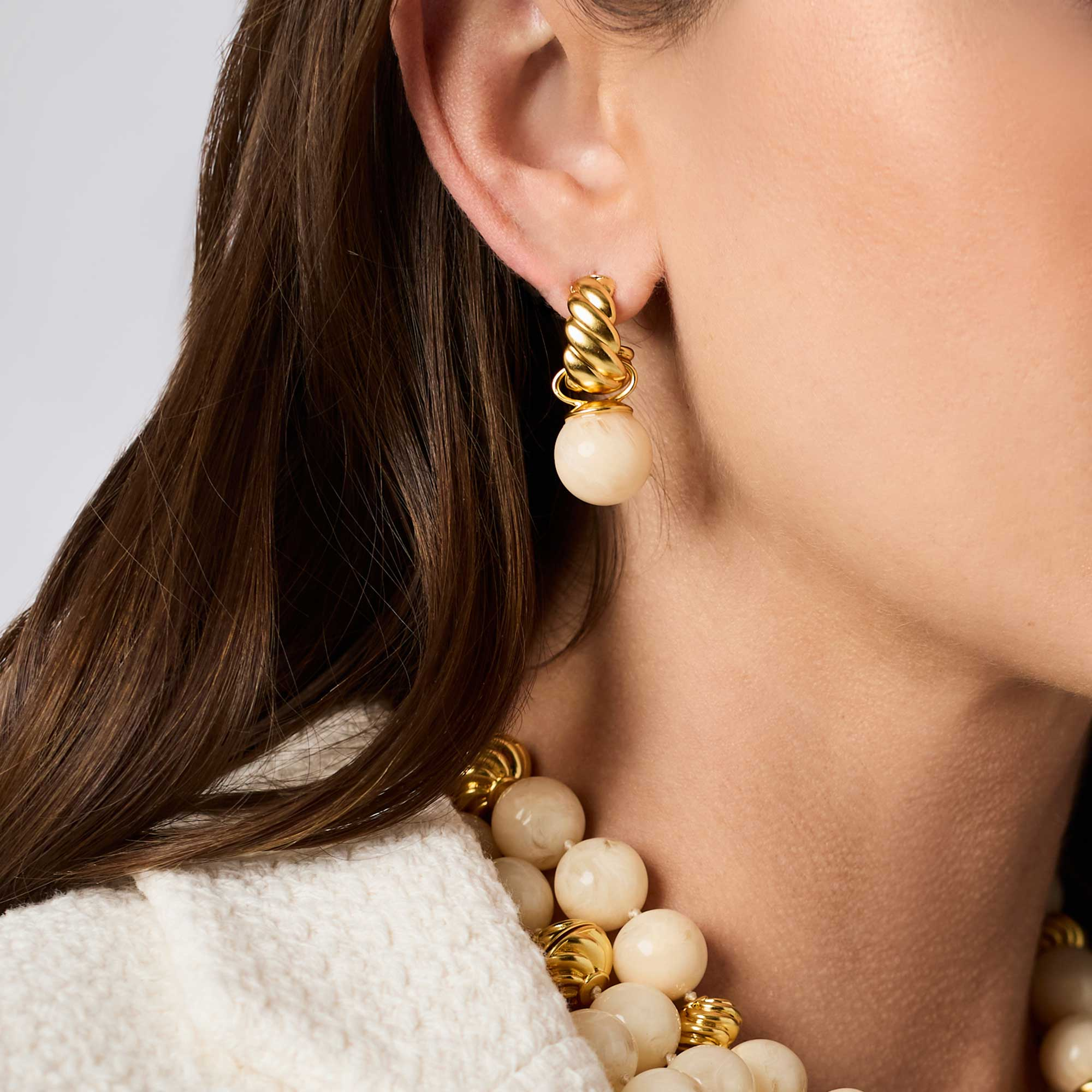 Woman wearing a Ravello Hoop & Charm Earring in 24K gold plate with a cream resin charm.