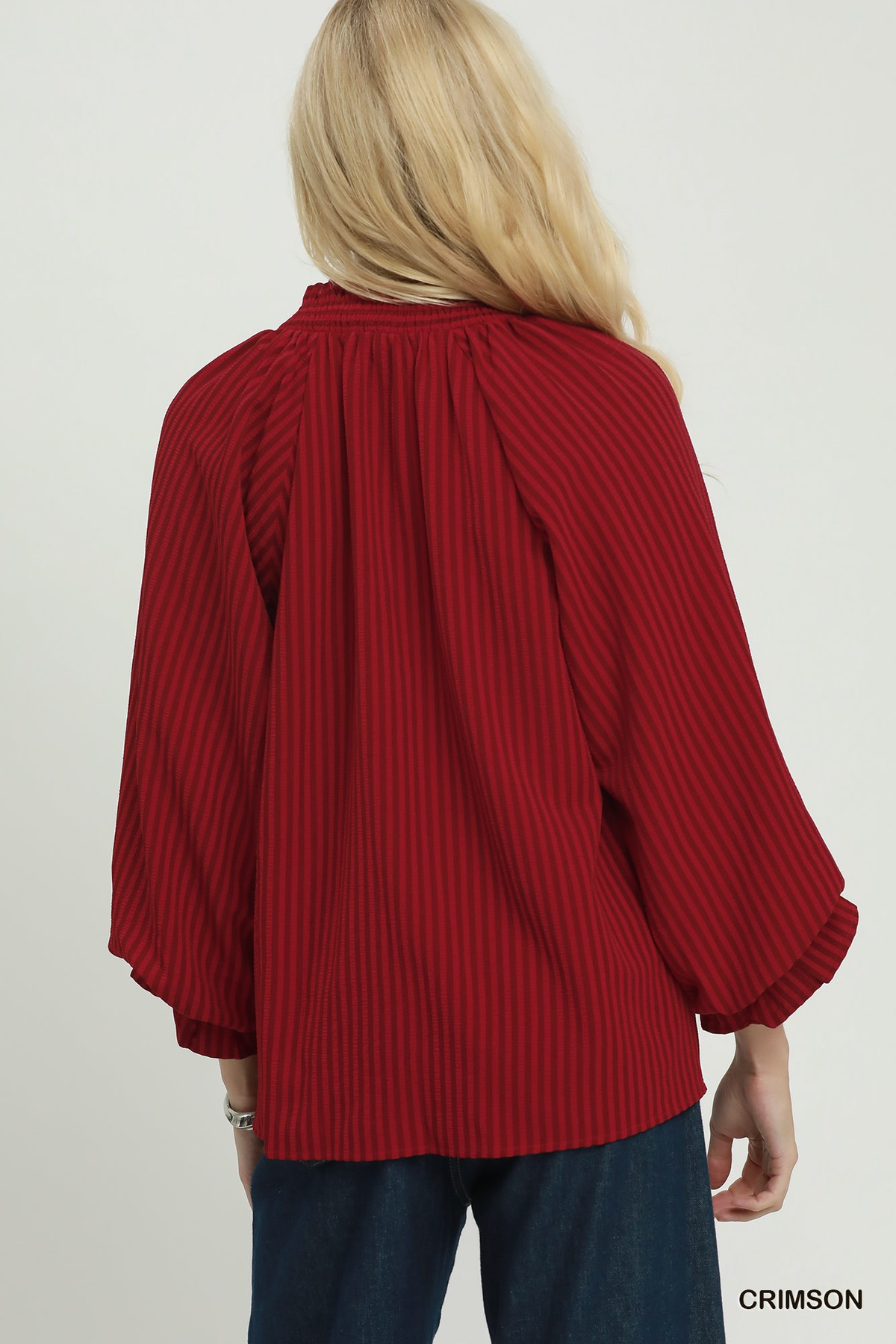 Back view of a woman wearing a crimson red striped Emma blouse with long puff sleeves.