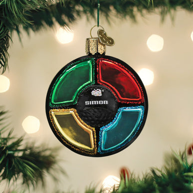 Simon game Christmas ornament hanging on a tree, featuring green, red, yellow, and blue panels.
