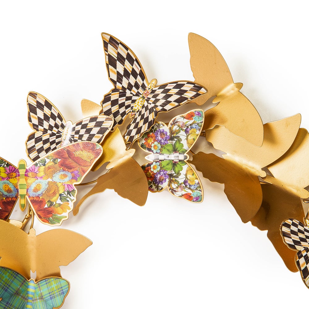 Close-up of a metal Butterfly Wreath featuring gold, checkered, and floral patterned butterflies.