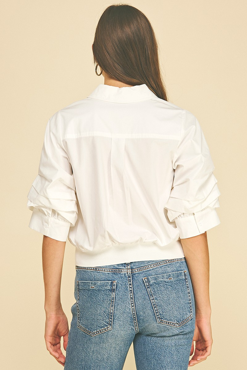 Back view of a white Jaycee cropped shirt with pleated sleeves and a banded hem.