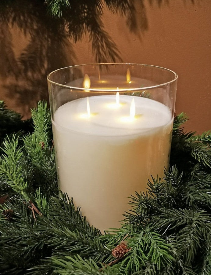 8-inch glass candle with 3 wicks lit, nestled in a green pine wreath.