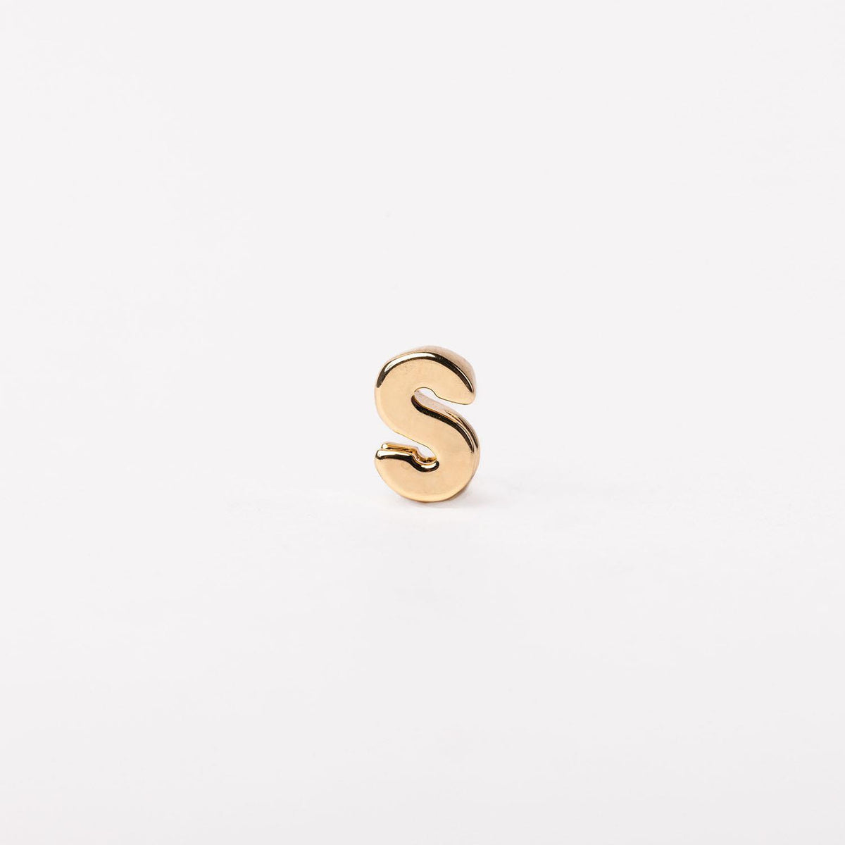 A small, polished gold-tone letter S charm with a rounded, three-dimensional silhouette.
