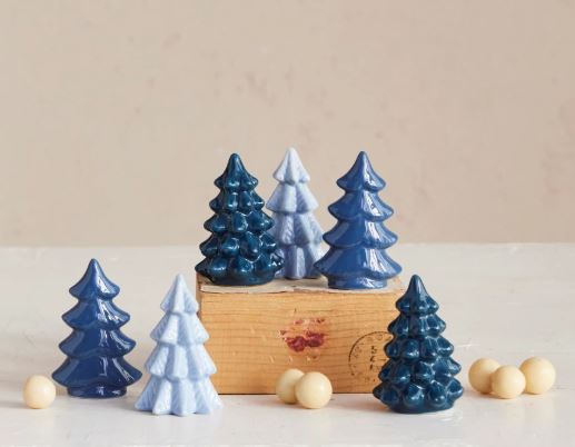 A collection of small blue and light blue stoneware Christmas tree figurines on a wooden block.