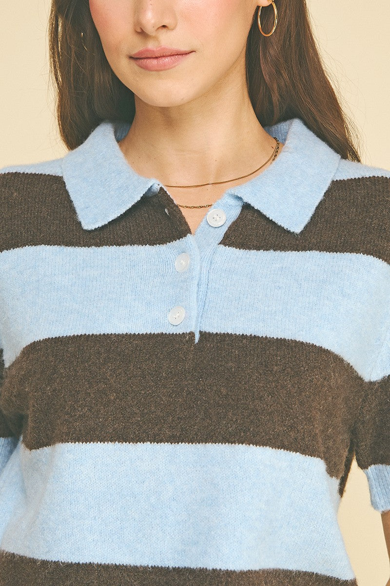 Close-up of a woman wearing a light blue and brown striped knit polo sweater with a collar.