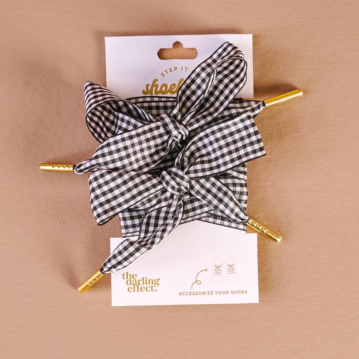 Black and white gingham patterned shoelaces with gold metal tips on a white display card.