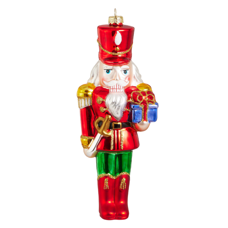 8.25-inch glass nutcracker ornament in a red uniform, green pants, and holding a blue gift box.