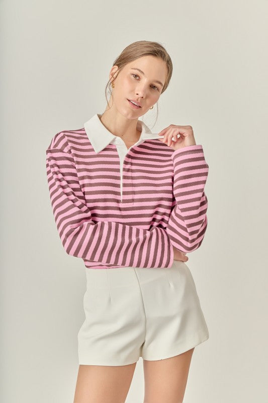 Woman wearing the Gina Rugby Polo Shirt in pink and brown stripes with white high-waisted shorts.