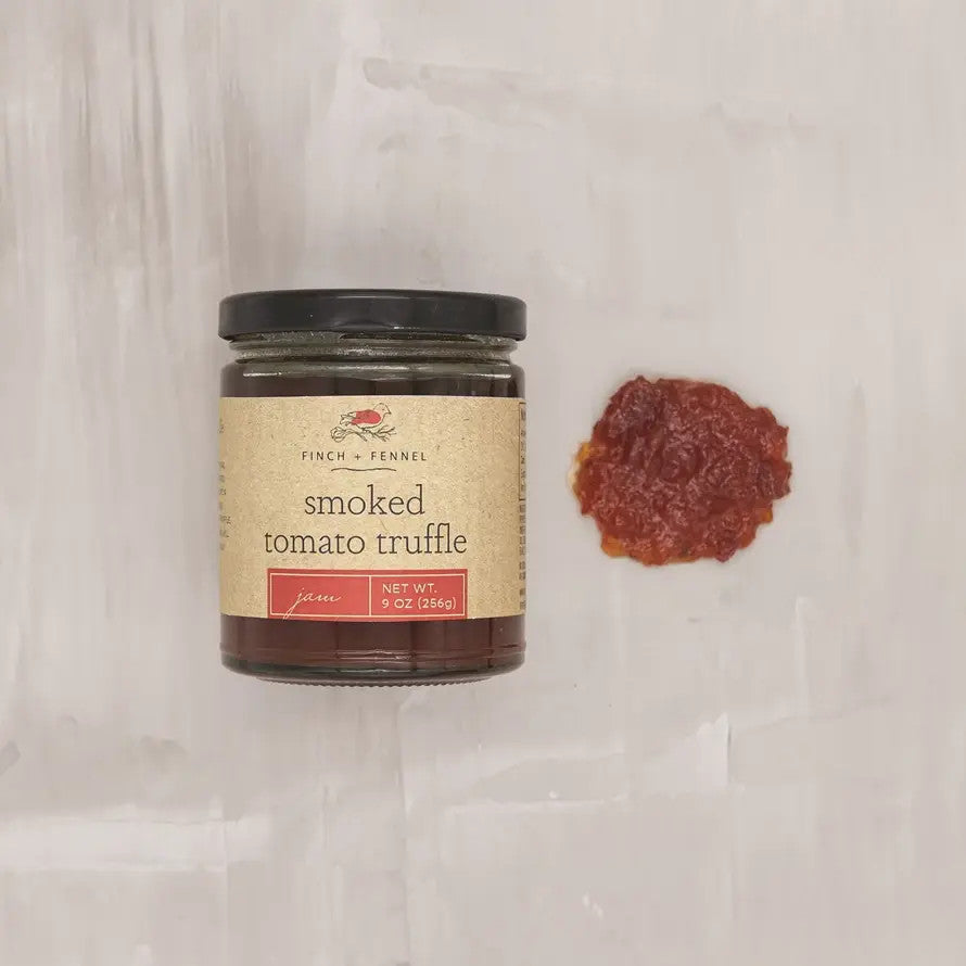 A jar of Finch + Fennel Smoked Tomato Truffle Jam next to a small dollop of the red jam.