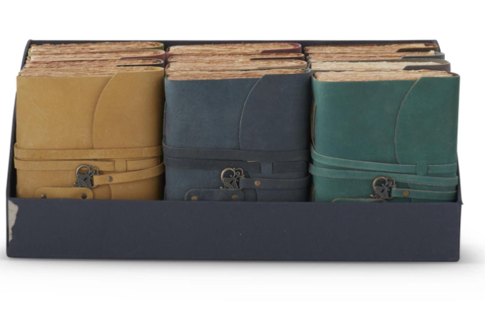 A display box containing several 8-inch handcrafted leather journals with key closures.