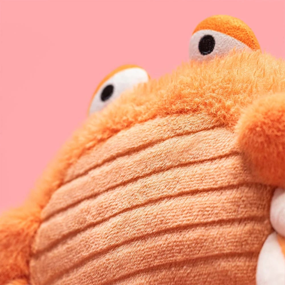 Close-up of an orange Jellycat Pinchsnap Crab plush toy with corduroy belly and embroidered eyes.