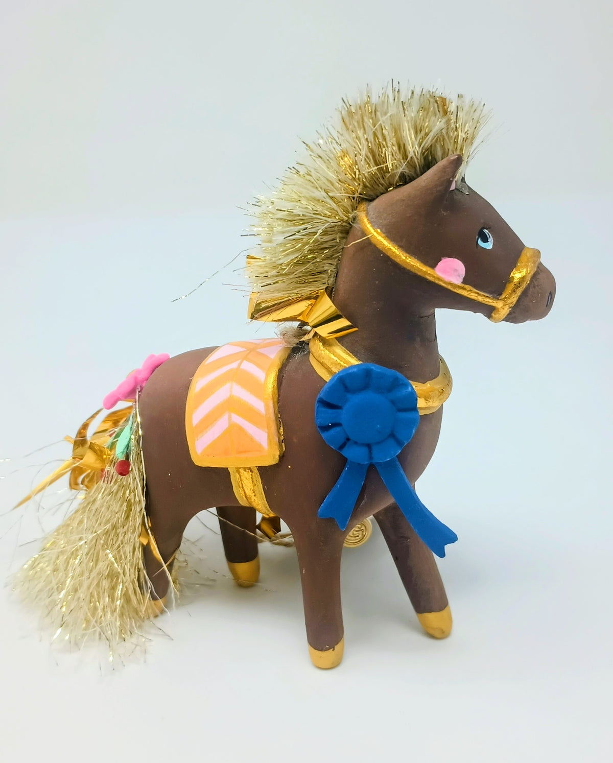 4-inch brown horse ornament with gold tinsel mane and tail, blue ribbon, and pink saddle.