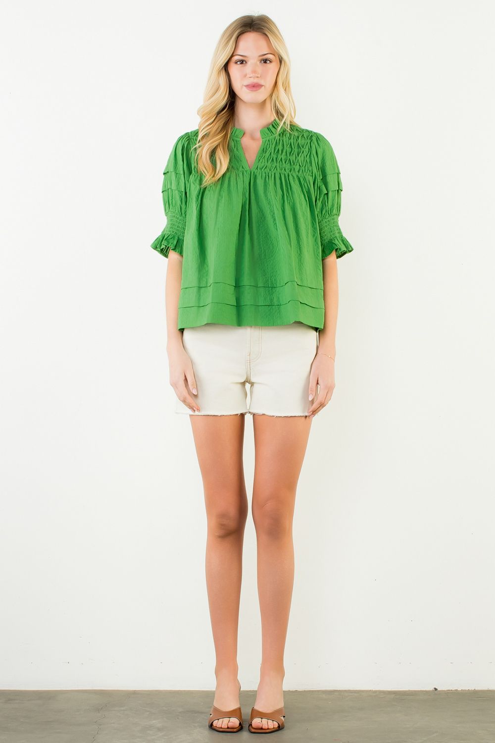 Woman wearing a white short-sleeve crinkle cotton top with relaxed silhouette.