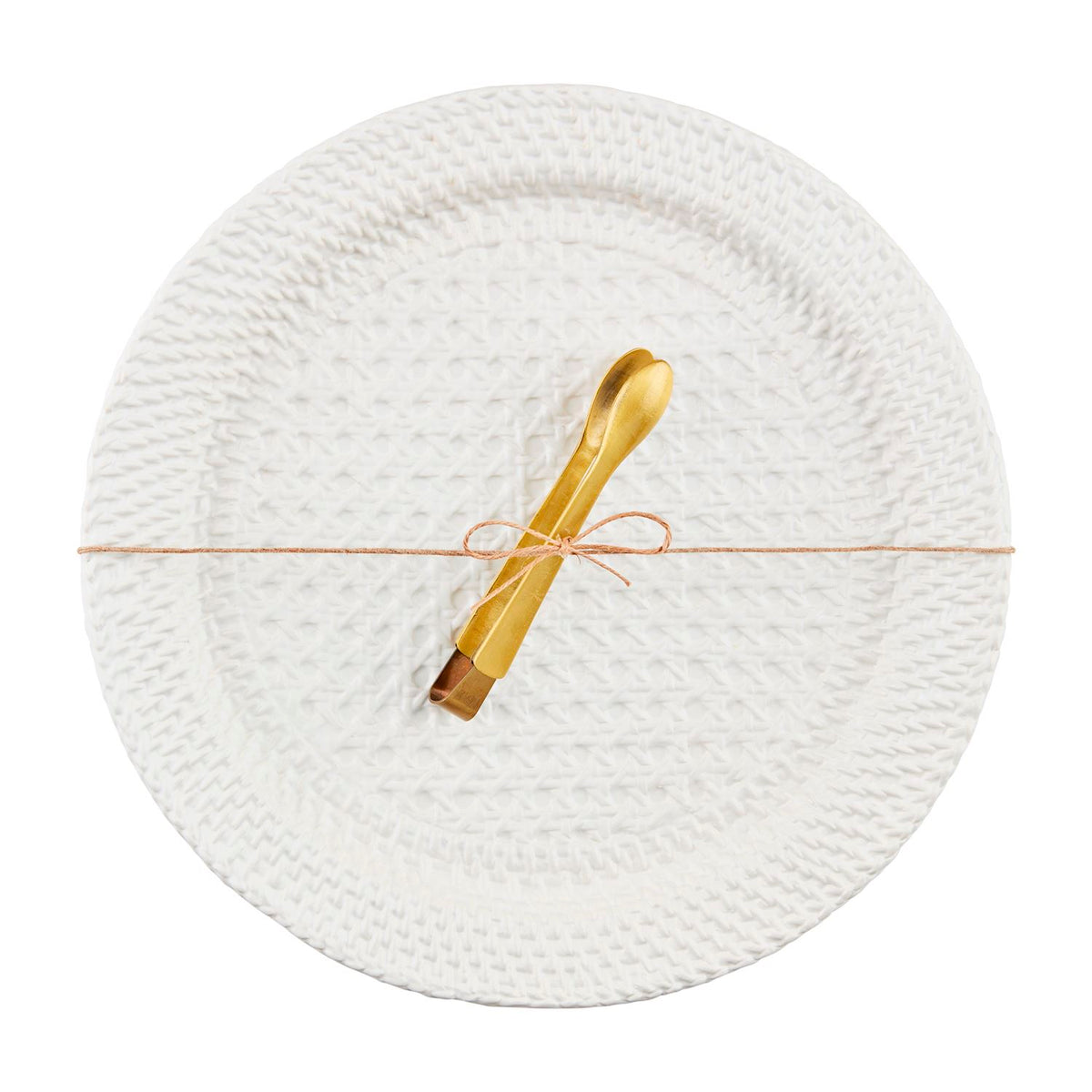 Round white woven stoneware platter with gold tongs tied with a thin brown string.