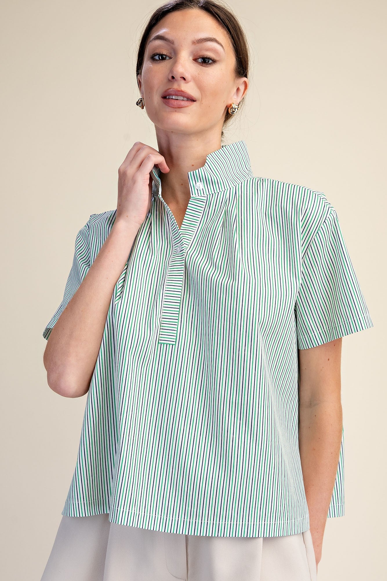 Woman wearing a Sarah Stripe Shirt with a stand collar, short sleeves, and green and white stripes.