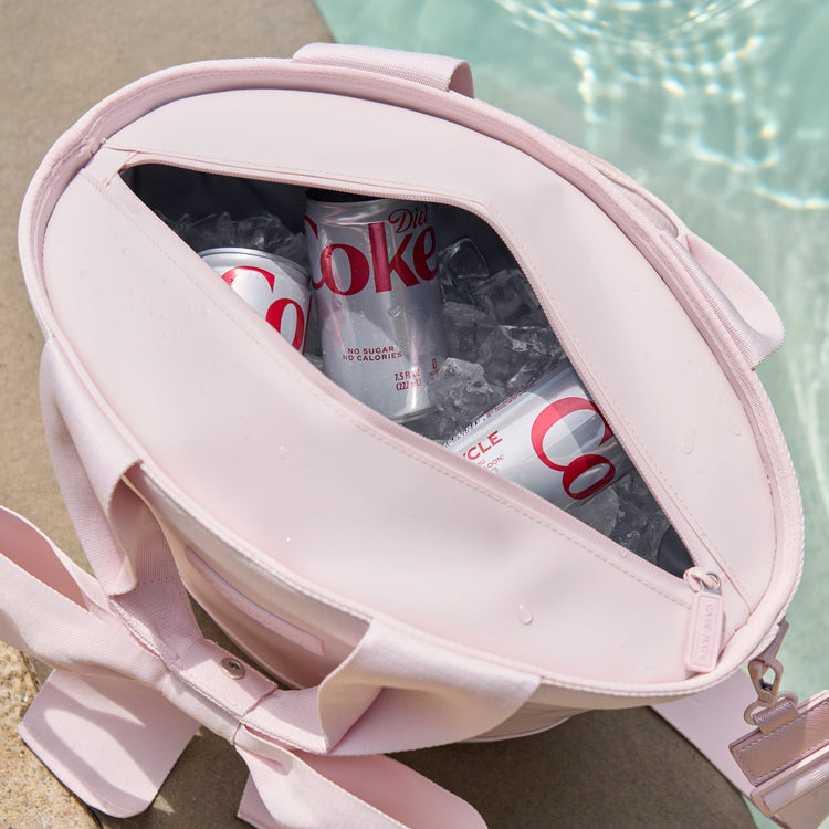 Top view of a ballet pink 7L jelly cooler tote with a bow, filled with ice and Diet Coke cans.