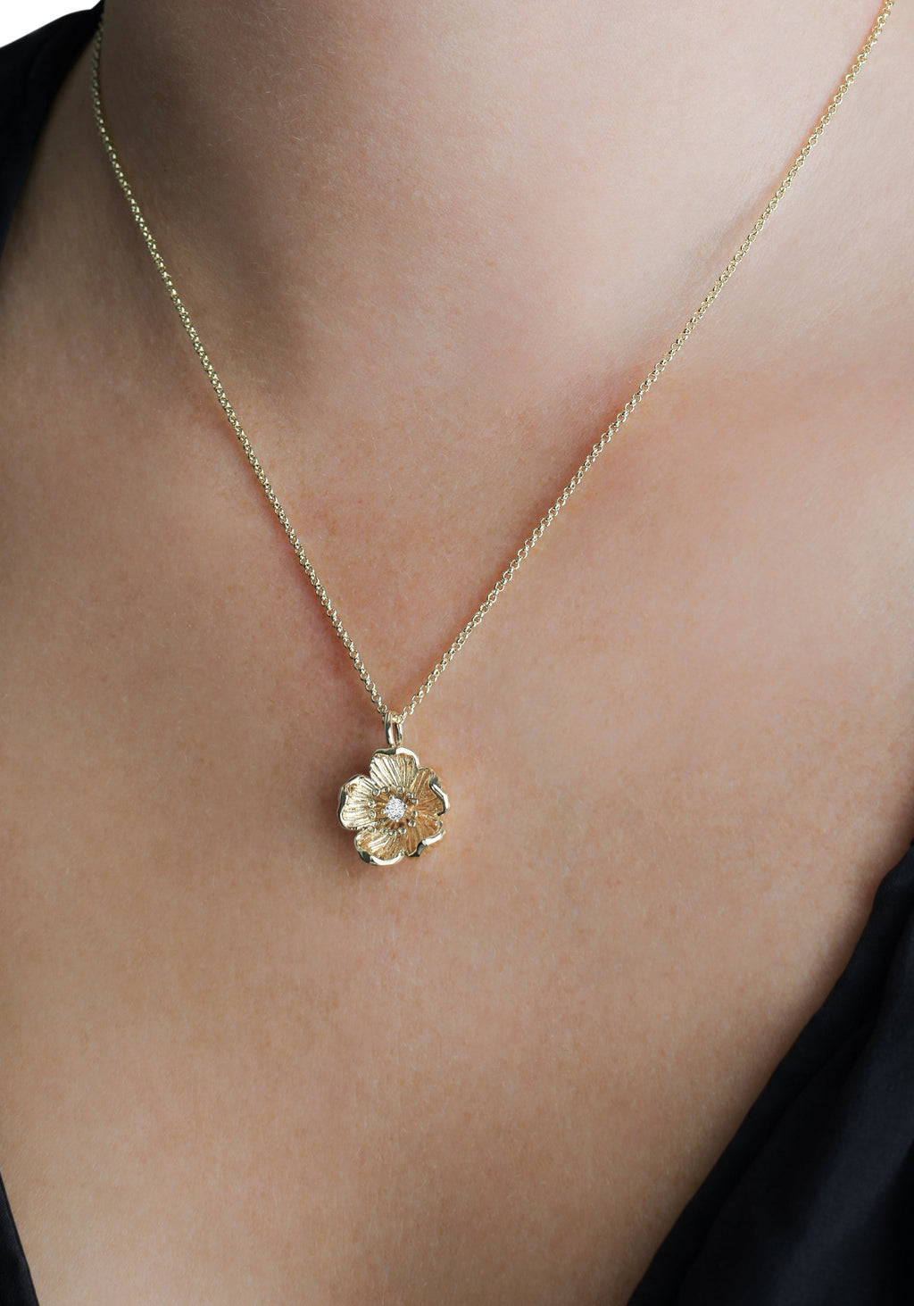 Wildflowers gold pendant necklace featuring a sculpted flower with a crystal center on a model.