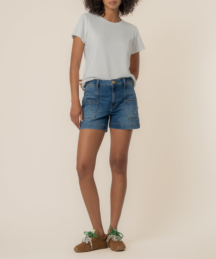 Woman wearing Jane high-rise denim shorts with large front pork chop pockets and a white t-shirt.