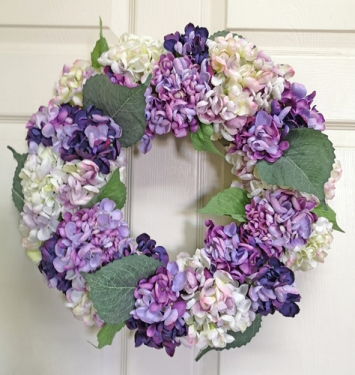 Round hydrangea wreath with soft pink blooms on a natural green base.