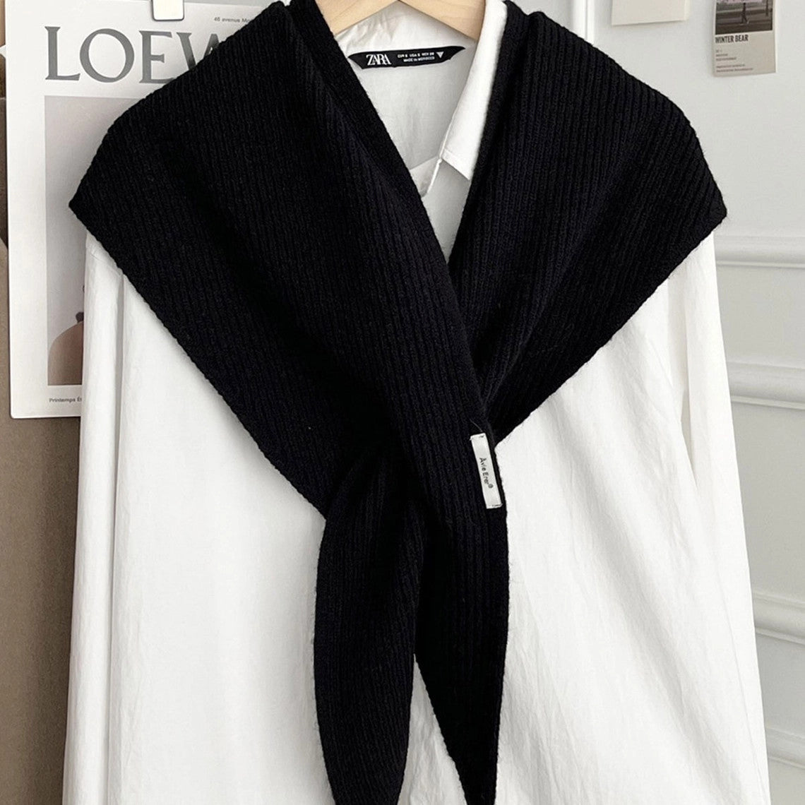Black knitted solid cross triangle shawl draped over a white button-down shirt on a hanger.