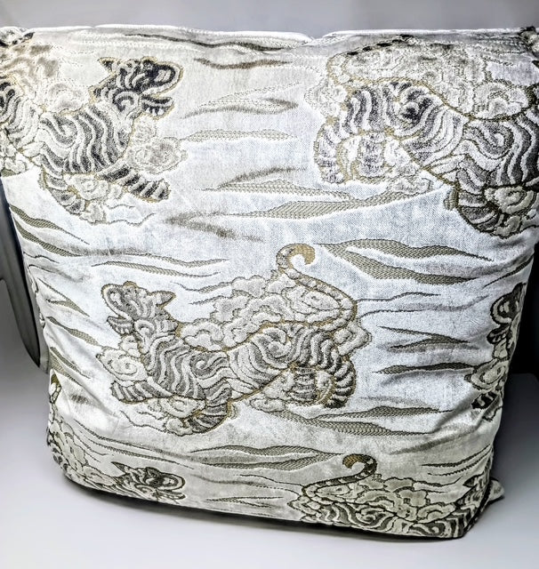 A 24x24 hand-crafted pillow with a white background and a detailed pattern of tigers and clouds in grey and gold.
