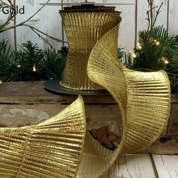 A roll of 5-inch wide gold fluted lame ribbon displayed on a rustic wooden surface.