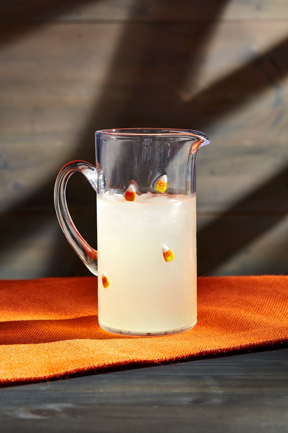 Yellow candy corn pitcher with orange accents and a festive autumn leaf pattern.