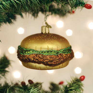 Glass chicken sandwich Christmas ornament with a golden bun, green lettuce, and breaded patty.