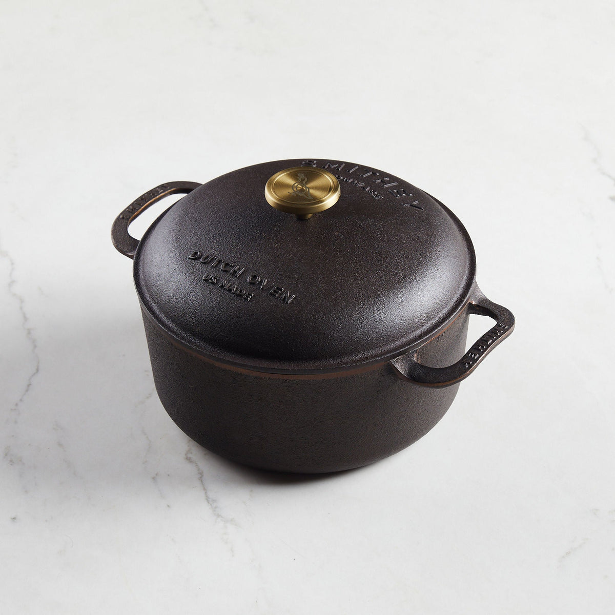 5.5 Qt Dutch Oven with a domed lid, brass knob, and side handles on a white marble surface.