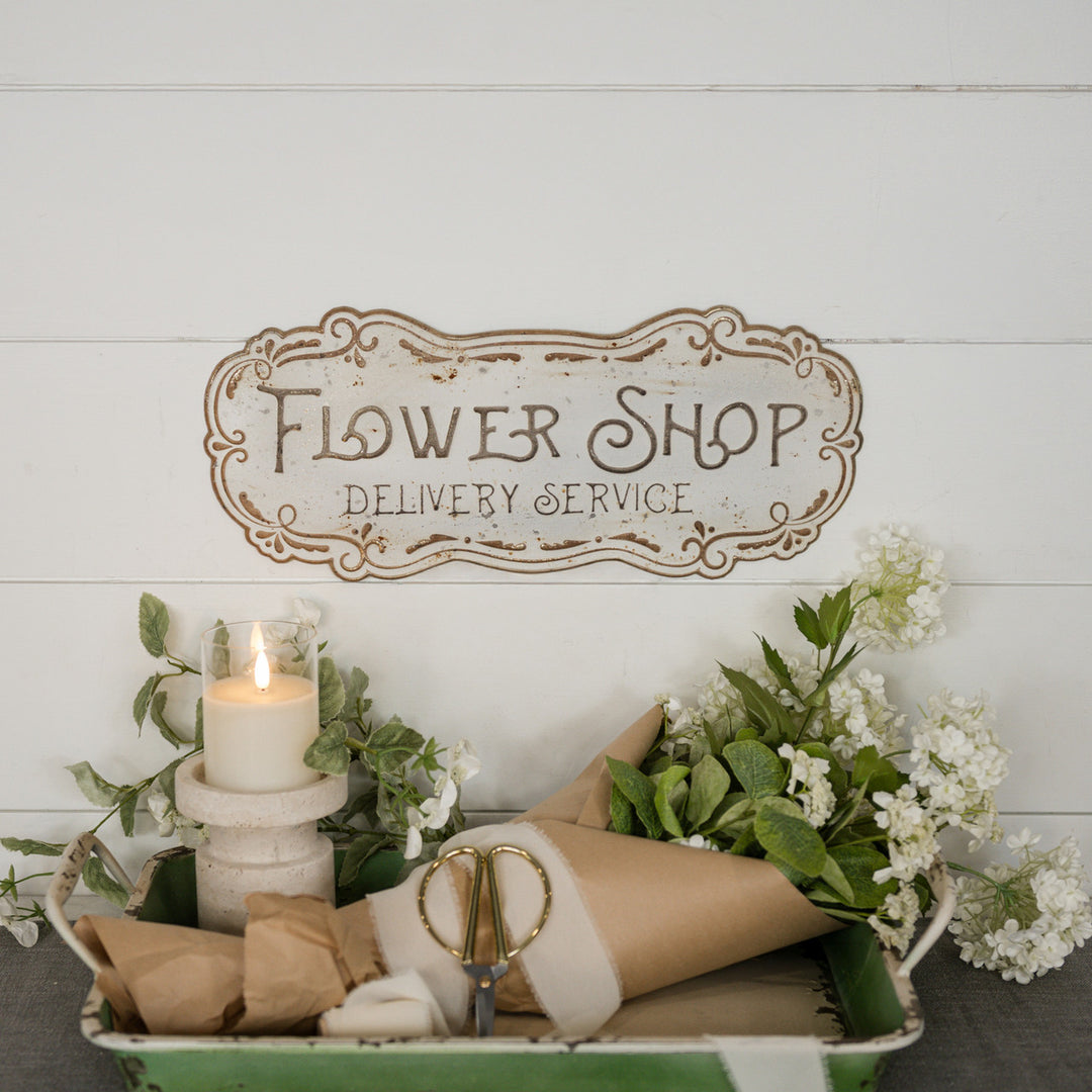 Metal flower shop sign with a vintage-style floral illustration on a white background.