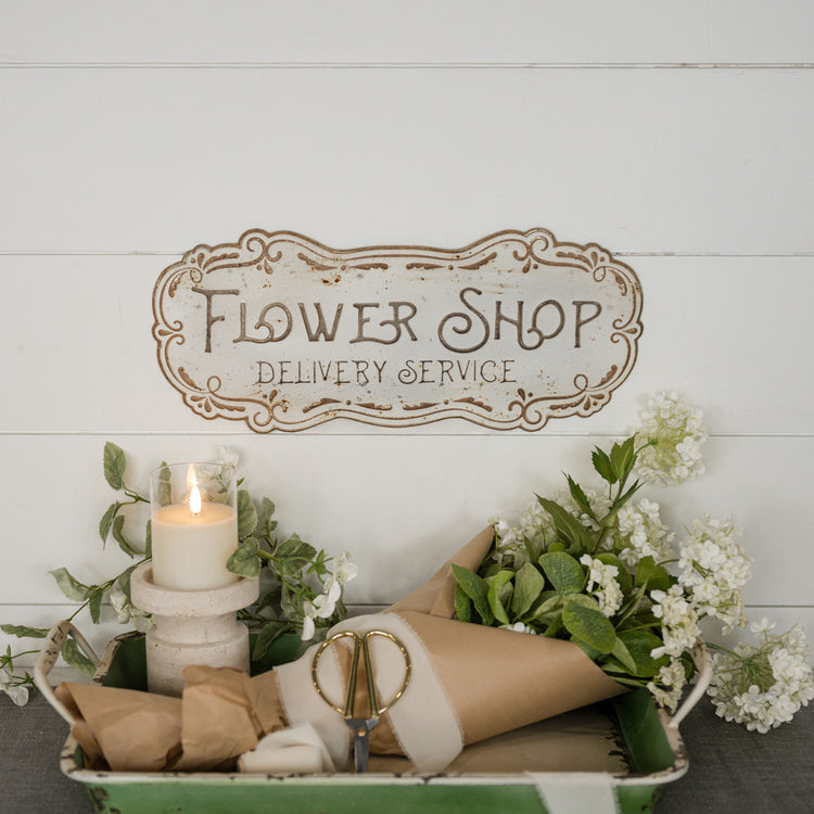 Metal flower shop sign with a vintage-style floral illustration on a white background.