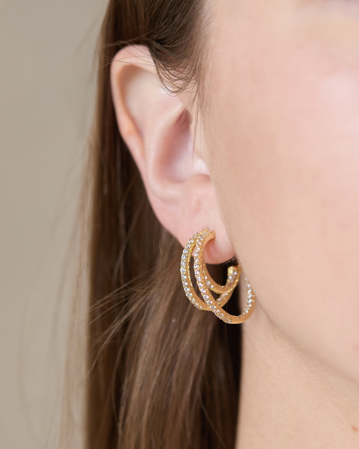 Maeve triple hoop earrings in polished gold metal with a stacked circular silhouette.