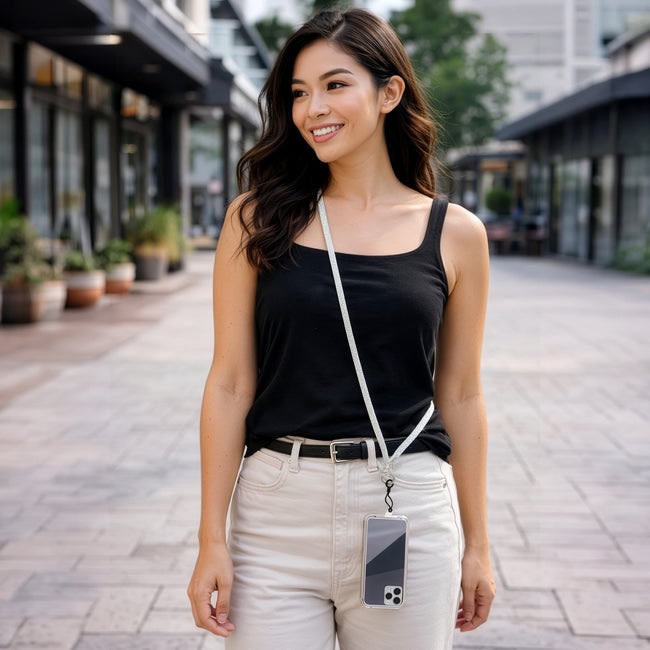 Woman wearing a white gemmed crossbody phone lanyard with silver hardware and a clear phone case.