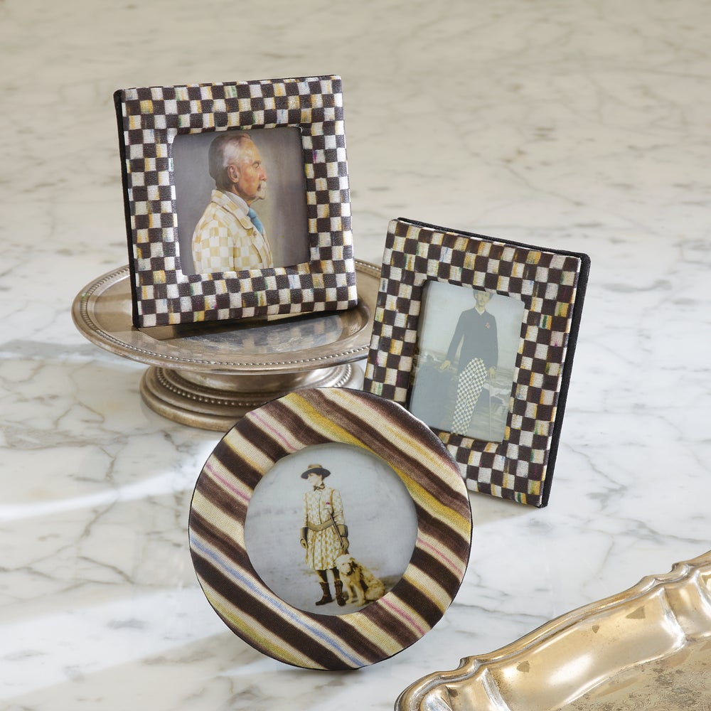 Set of three small picture frames in checkered and striped patterns on a marble surface.