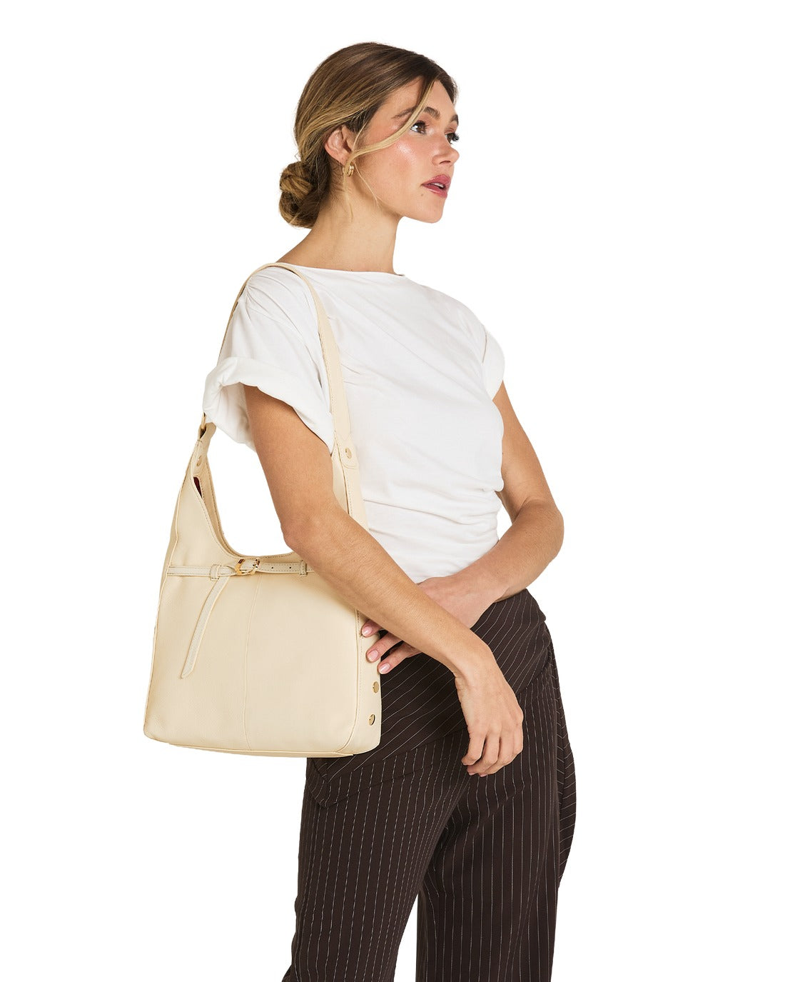 Woman wearing the Tim Med-Belted hobo bag in parchment leather with gold hardware.
